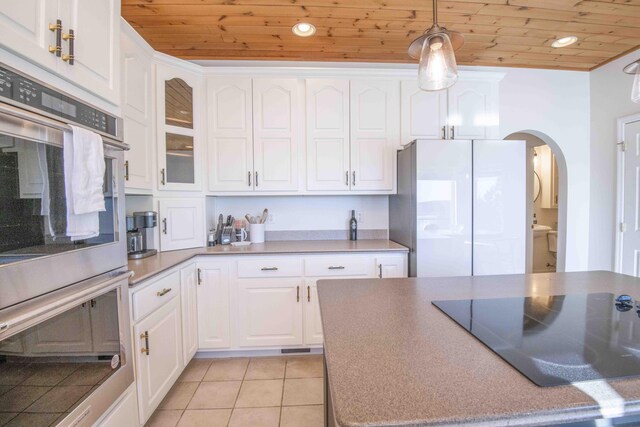 kitchen featuring arched walkways, wooden ceiling, freestanding refrigerator, and black electric cooktop