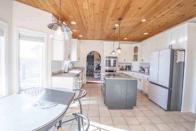 kitchen featuring light tile patterned floors, double oven, freestanding refrigerator, wood ceiling, and a sink