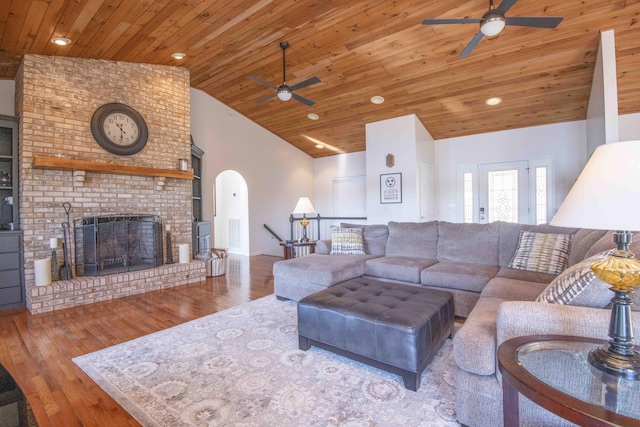 living room featuring a ceiling fan, hardwood / wood-style flooring, wood ceiling, a brick fireplace, and high vaulted ceiling