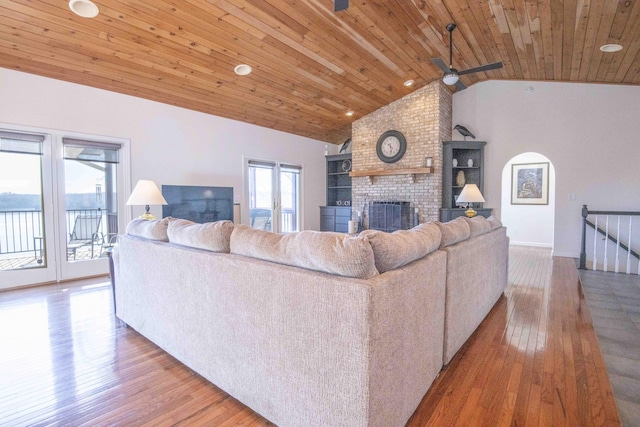 living area featuring lofted ceiling, wood ceiling, a fireplace, and plenty of natural light