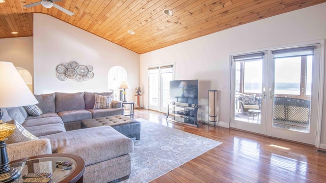 living area with arched walkways, a ceiling fan, wood ceiling, wood finished floors, and french doors