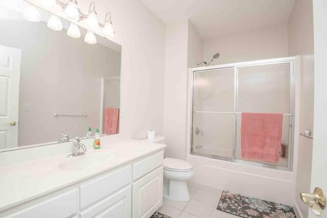 bathroom featuring toilet, tile patterned flooring, enclosed tub / shower combo, and vanity