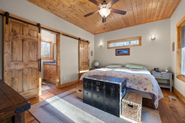 bedroom featuring wood ceiling, a barn door, and visible vents