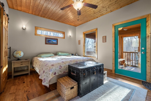 bedroom with wood finished floors, wooden ceiling, multiple windows, and a barn door