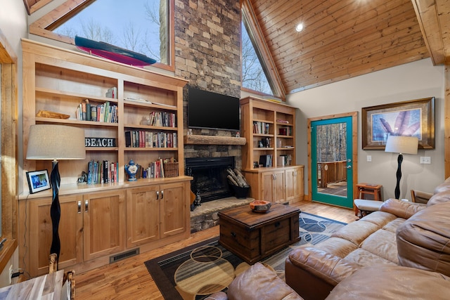 living room with light wood-type flooring, a stone fireplace, wooden ceiling, and visible vents