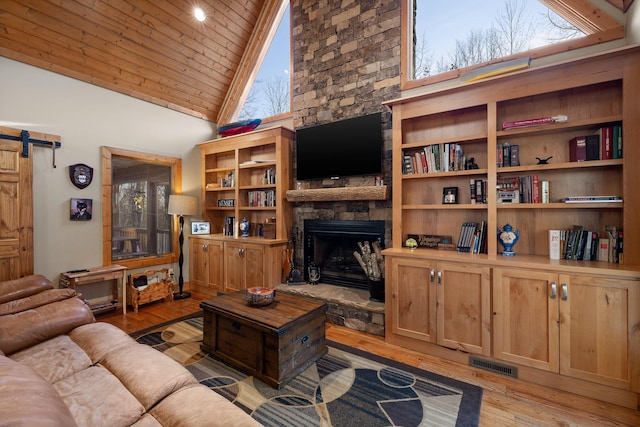 living area with a barn door, wooden ceiling, a fireplace, visible vents, and light wood-type flooring