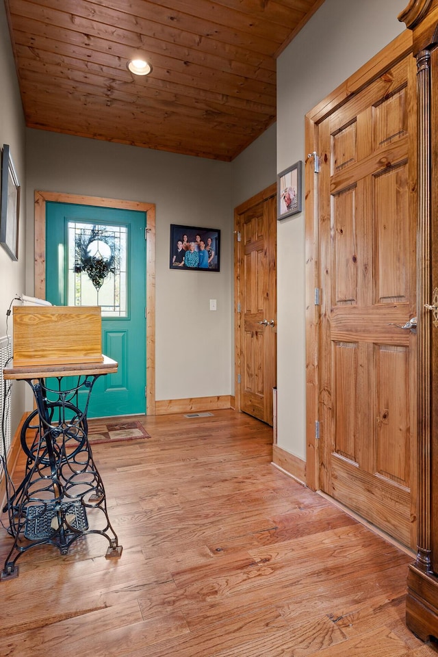 corridor with light wood-type flooring, wood ceiling, and baseboards