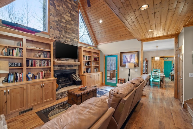 living area featuring a stone fireplace, wooden ceiling, light wood-style flooring, and visible vents