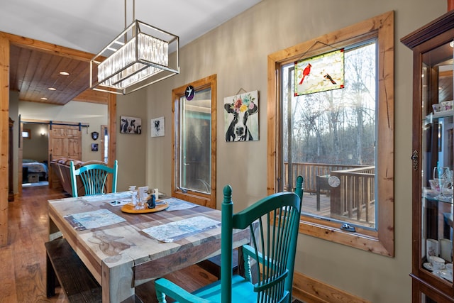 dining area featuring a barn door, recessed lighting, hardwood / wood-style flooring, and an inviting chandelier