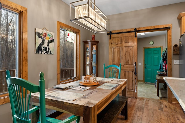 dining space featuring a barn door, a chandelier, and wood finished floors