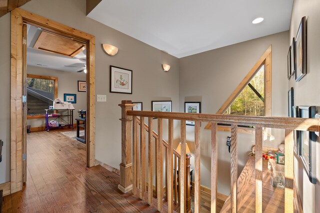 hallway with wood-type flooring, an upstairs landing, and baseboards