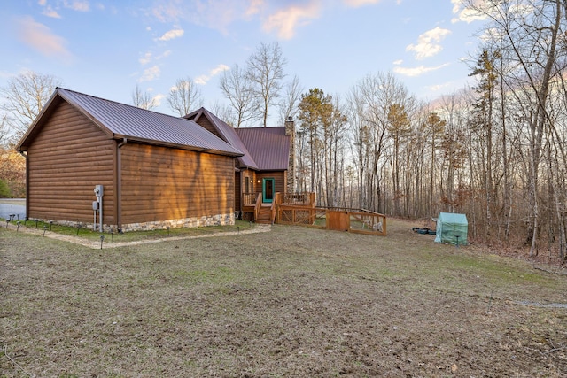 view of side of property with metal roof, a chimney, and a lawn