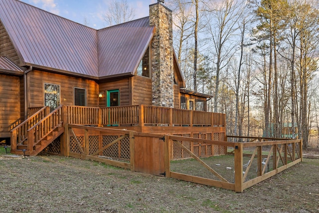 exterior space with faux log siding, a chimney, metal roof, stairs, and a deck