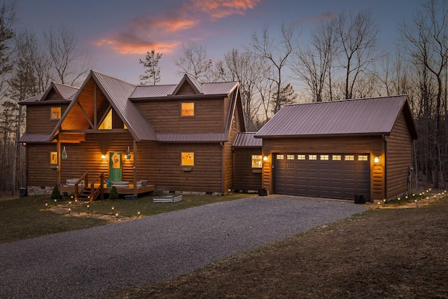 view of front of house featuring driveway, crawl space, faux log siding, and metal roof