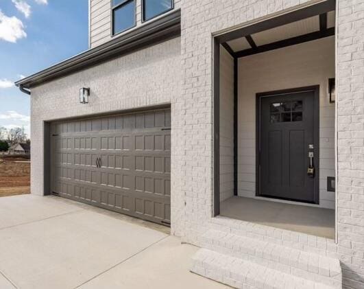 view of exterior entry with driveway and an attached garage