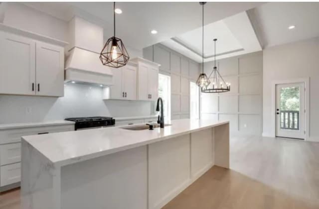 kitchen with a center island with sink, light countertops, light wood-style floors, a sink, and range