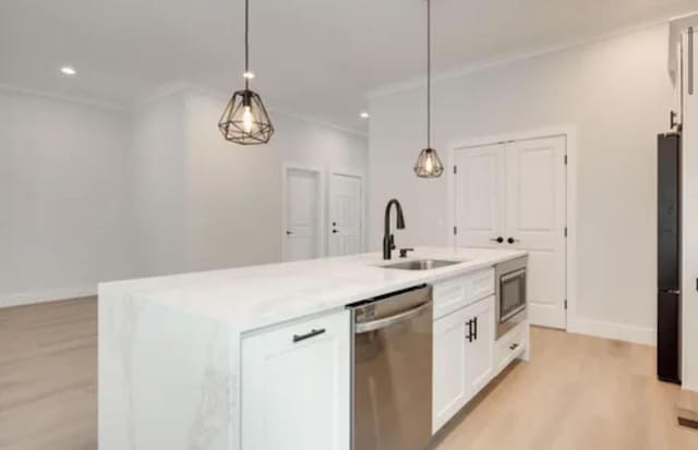 kitchen featuring stainless steel appliances, a sink, white cabinetry, an island with sink, and pendant lighting