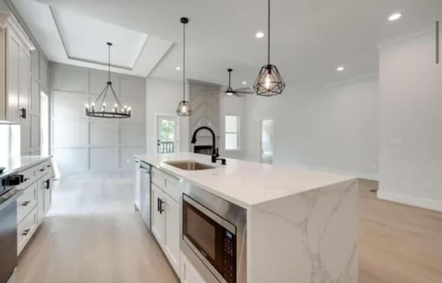 kitchen featuring hanging light fixtures, appliances with stainless steel finishes, white cabinets, and a sink