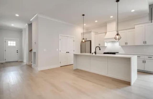 kitchen featuring light countertops, light wood-style flooring, custom exhaust hood, and fridge