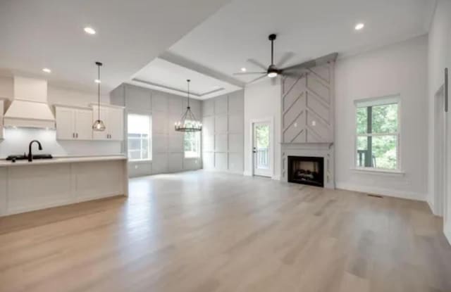 unfurnished living room featuring a premium fireplace, light wood-type flooring, a sink, and a wealth of natural light