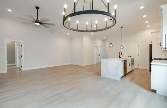 kitchen featuring a sink, white cabinetry, open floor plan, and stainless steel dishwasher