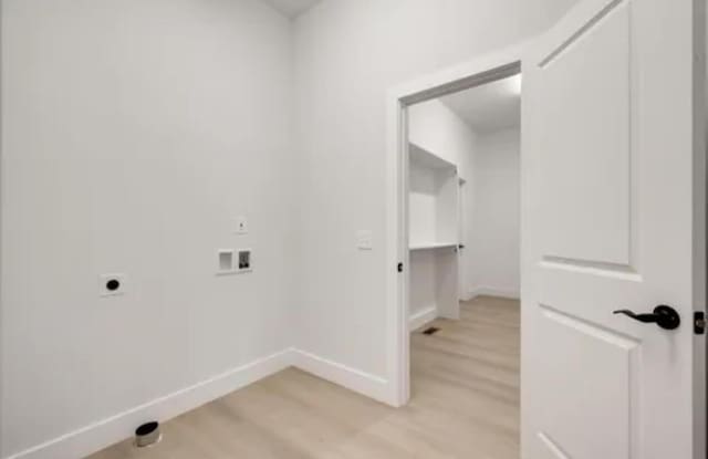 washroom featuring laundry area, baseboards, hookup for a washing machine, light wood-type flooring, and electric dryer hookup