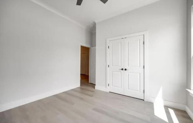 unfurnished bedroom featuring ceiling fan, wood finished floors, baseboards, vaulted ceiling, and a closet