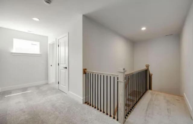 hallway featuring carpet, baseboards, an upstairs landing, and recessed lighting