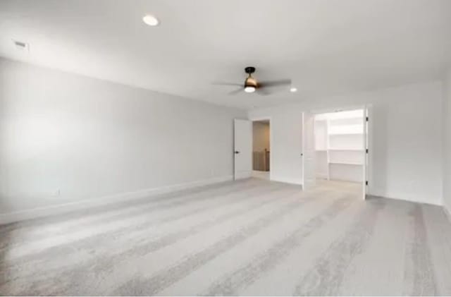 unfurnished bedroom featuring a spacious closet, baseboards, wood finished floors, and recessed lighting