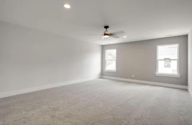 carpeted spare room with recessed lighting, a ceiling fan, and baseboards