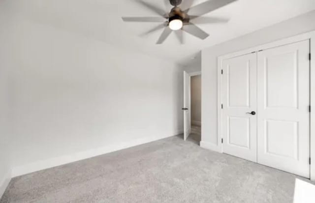 unfurnished bedroom featuring ceiling fan, a closet, baseboards, and light colored carpet