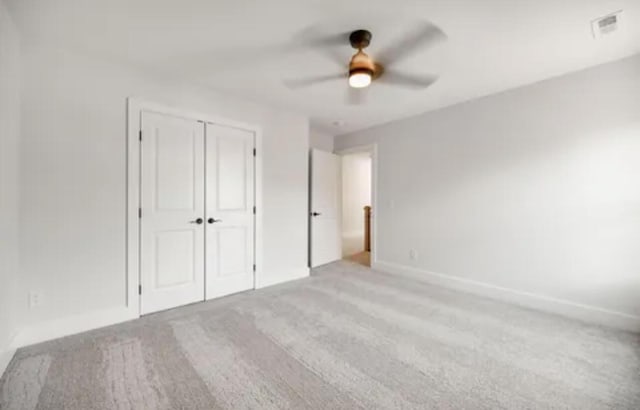 unfurnished bedroom with a closet, light colored carpet, ceiling fan, and visible vents