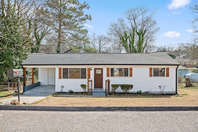 ranch-style home featuring driveway, a shingled roof, and a carport