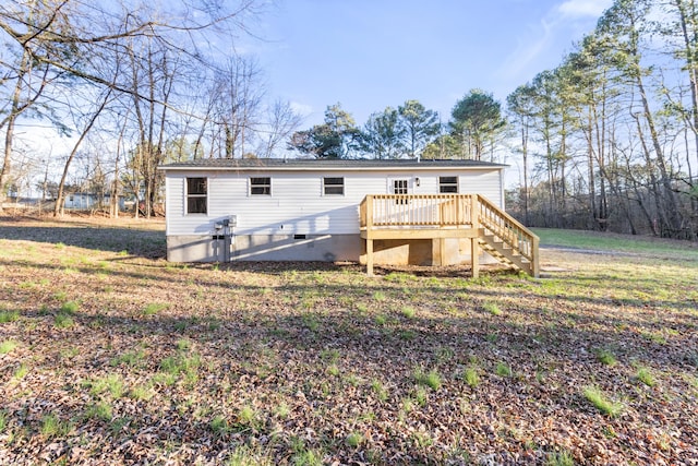 back of property featuring a lawn, a deck, and stairs