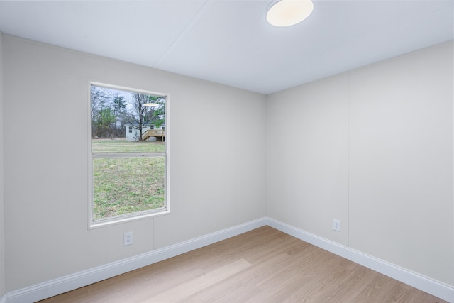 empty room with plenty of natural light, wood finished floors, and baseboards