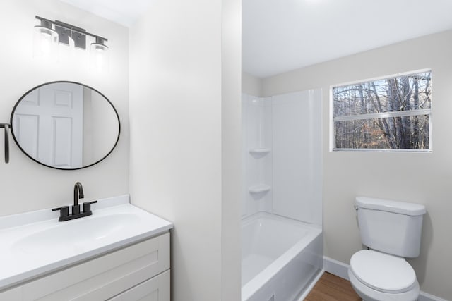 bathroom featuring baseboards, toilet, shower / tub combination, wood finished floors, and vanity