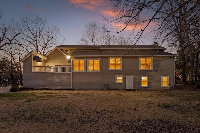 back of property at dusk with a chimney and central AC