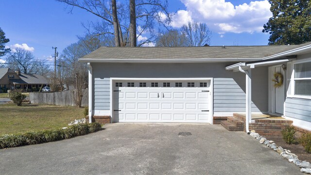 garage featuring driveway and fence