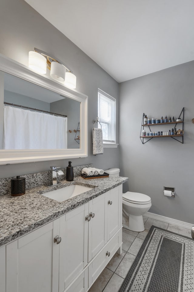 bathroom with baseboards, vanity, toilet, and tile patterned floors