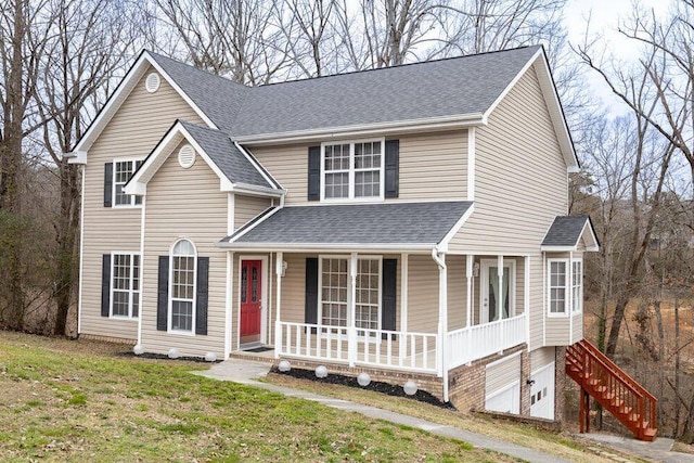 traditional-style home featuring covered porch, a shingled roof, and a front lawn