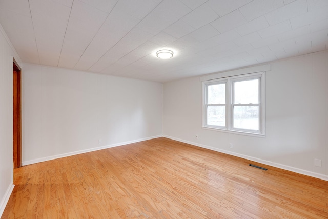 unfurnished room featuring light wood finished floors, visible vents, and baseboards