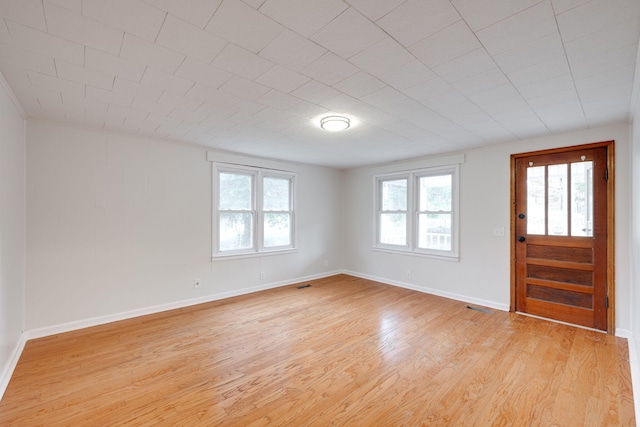 foyer entrance featuring light wood-style floors, a wealth of natural light, visible vents, and baseboards