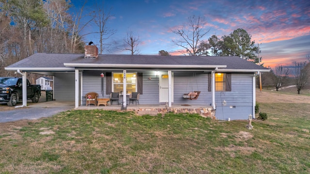 ranch-style home with a carport, a lawn, a chimney, and driveway