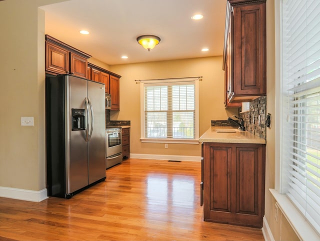 kitchen with tasteful backsplash, appliances with stainless steel finishes, light wood-style floors, a sink, and recessed lighting