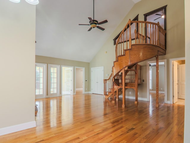 unfurnished living room featuring stairs, a ceiling fan, baseboards, and wood finished floors