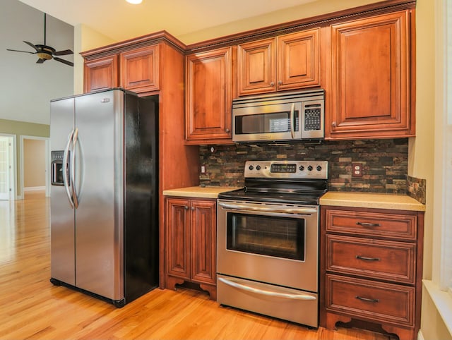 kitchen featuring light wood-style flooring, stainless steel appliances, backsplash, and light countertops