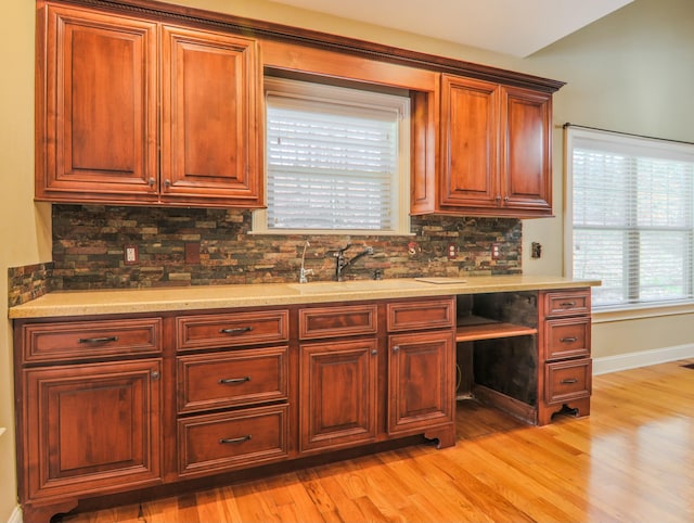 kitchen featuring light wood finished floors, backsplash, and a sink