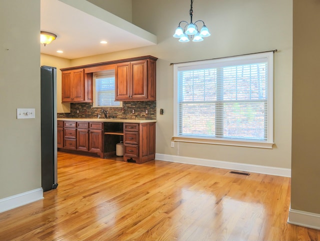 kitchen with brown cabinets, baseboards, visible vents, and decorative backsplash