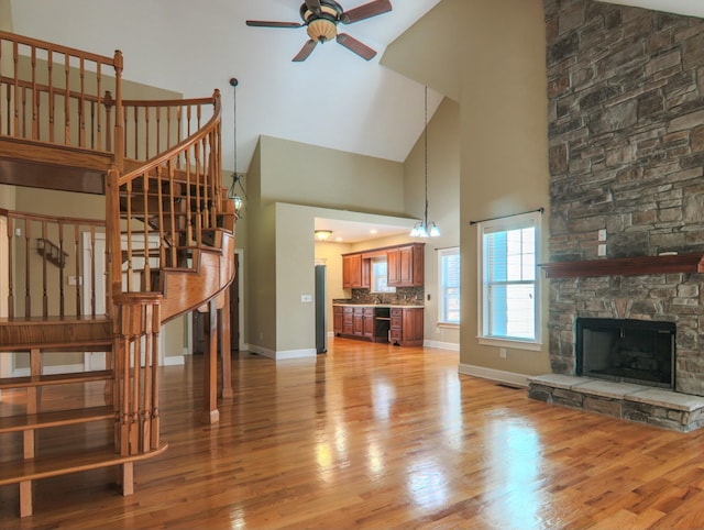 unfurnished living room featuring baseboards, a ceiling fan, stairs, light wood-type flooring, and a fireplace