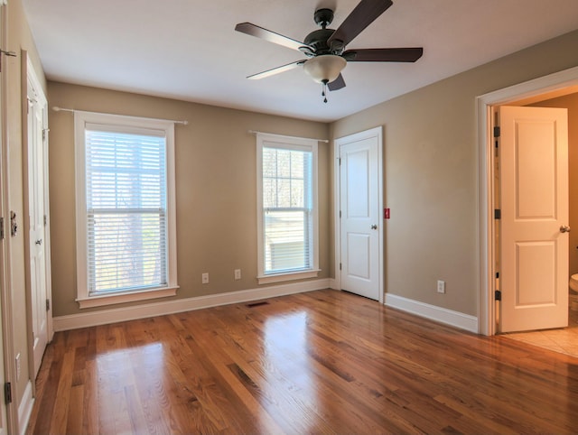 unfurnished bedroom featuring a ceiling fan, visible vents, baseboards, and wood finished floors